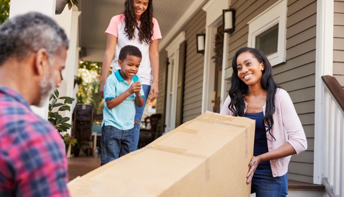 A couple moves in a box of furniture they had delivered.