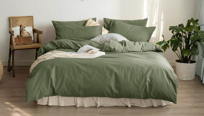 Un lit avec une couette verte et de nombreux oreillers dans une chambre à coucher de style bohème.