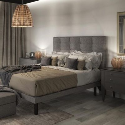 Une chambre faiblement éclairée, avec du linge de lit et du mobilier aux tons neutres.