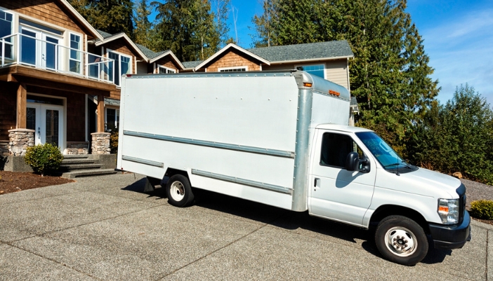 A white delivery truck outside a modern home.