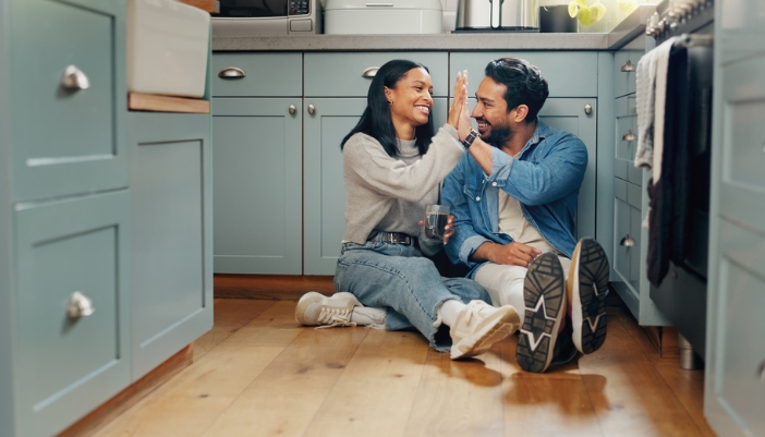 A couple sits together in their kitchen and looks around their space.