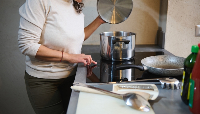 A woman changes the settings on her induction range at home.