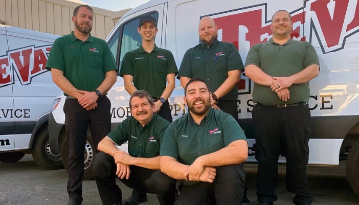 TeeVax delivery and service men gathered in front of a delivery vehicle.