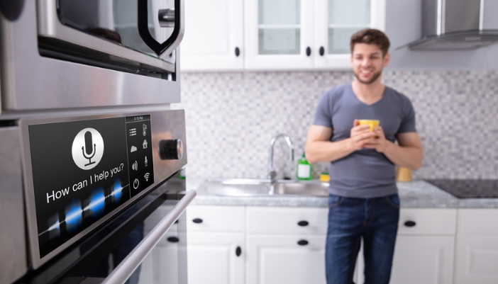 A man looks at his smart fridge in his kitchen.