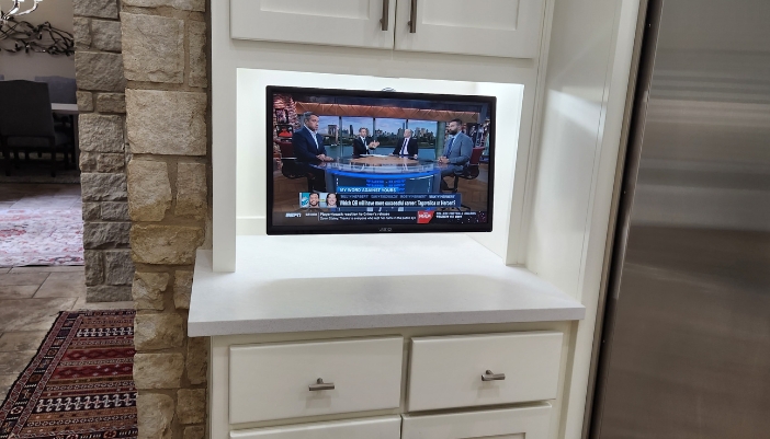 A tv mounted under a cabinet in a kitchen.