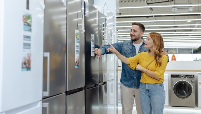 A couple shop for a refrigerator in an appliance showroom.