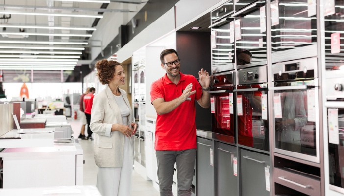A salesman works with a woman to look for a enw range.