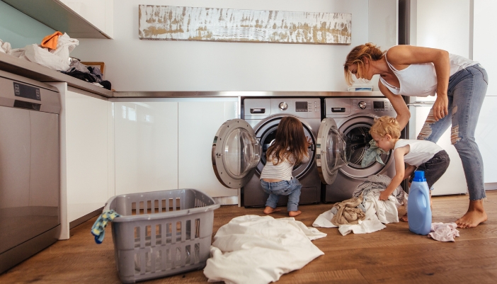 A mom and children do laundry together at home.