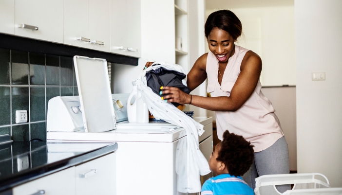 A mom happily changes a load over while her child watches.
