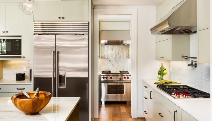 A luxury kitchen with stainless steel appliances and warm light.