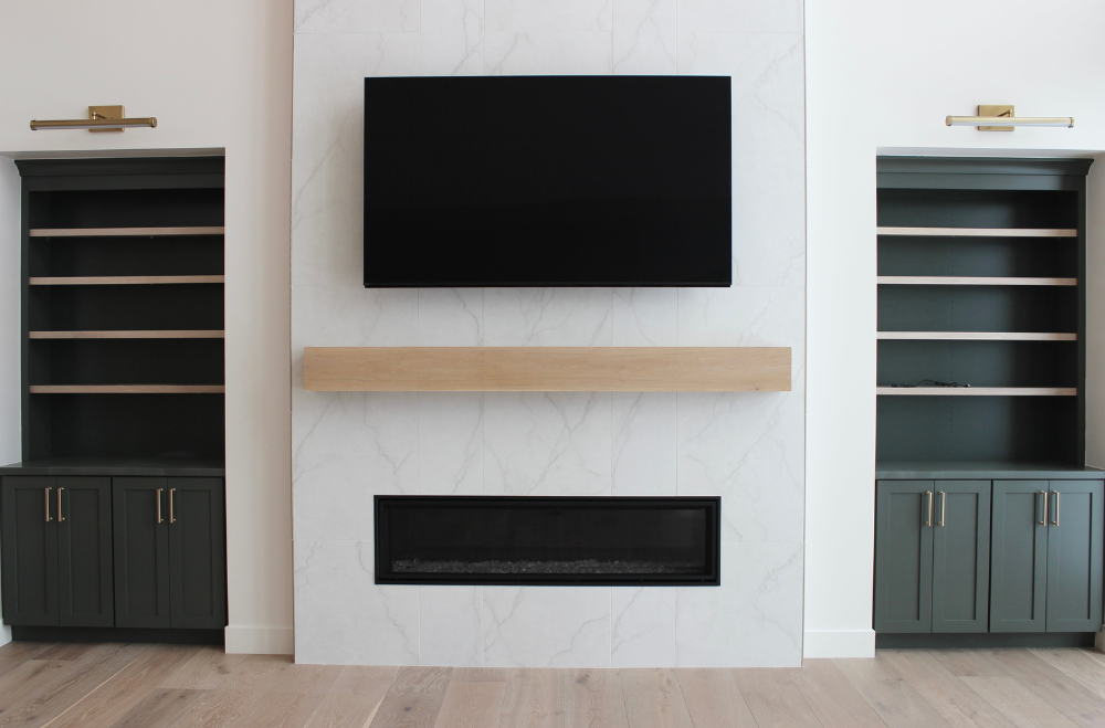 great room build in wall with dark green painted cabinets and white oak shelves on each side of the fireplace