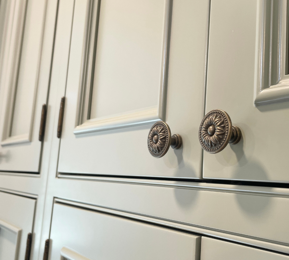 close up shot of evergreen fog green painted inset beaded frame cabinets with knob hardware