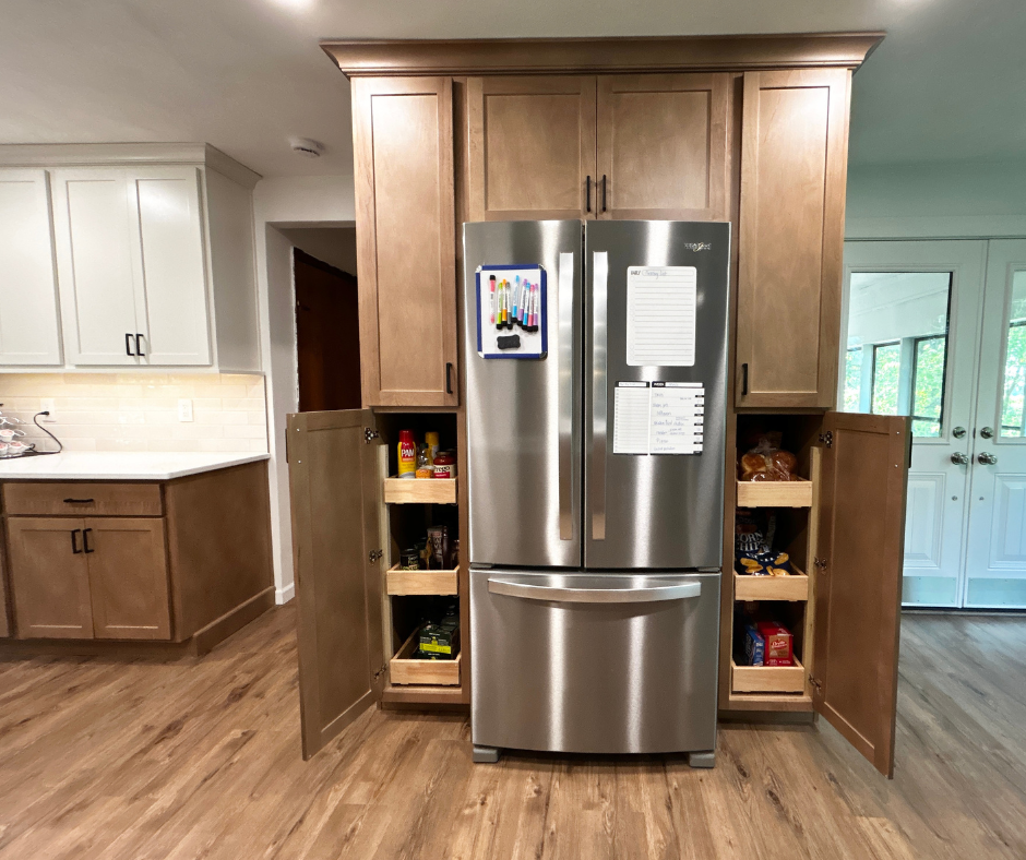 maple cabinets surrounding refrigerator with two deep pantries shown with doors open and sliding shelves inside