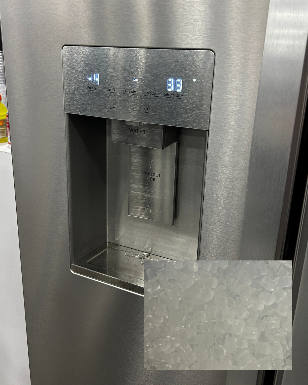 closeup of nugget ice dispenser in door of stainless steel refrigerator