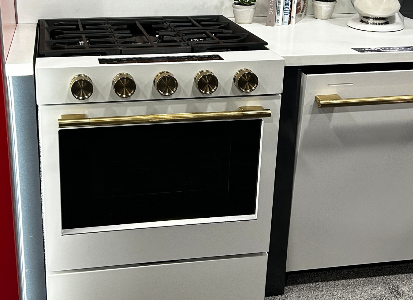 images of kitchenaid porcelain white with brass knobs and handles shown on range and dishwasher in a trade show booth