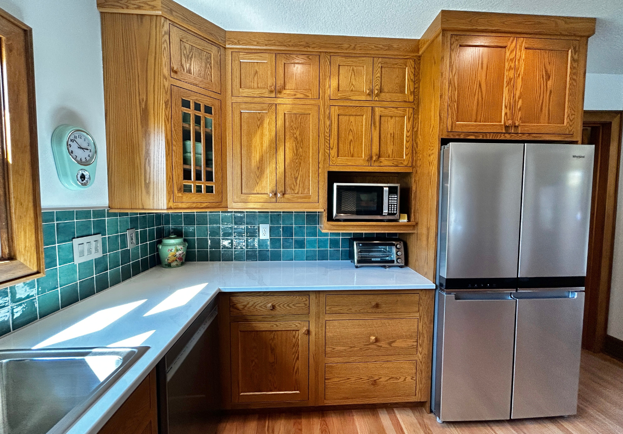 red oak inset kitchen design with green backsplash tile and stainless steel appliances