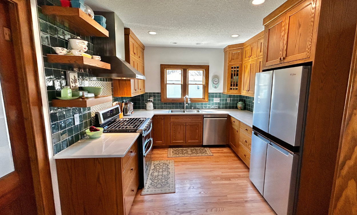 view into u-shaped kitchen remodel with red oak inset cabinets and green wall tile