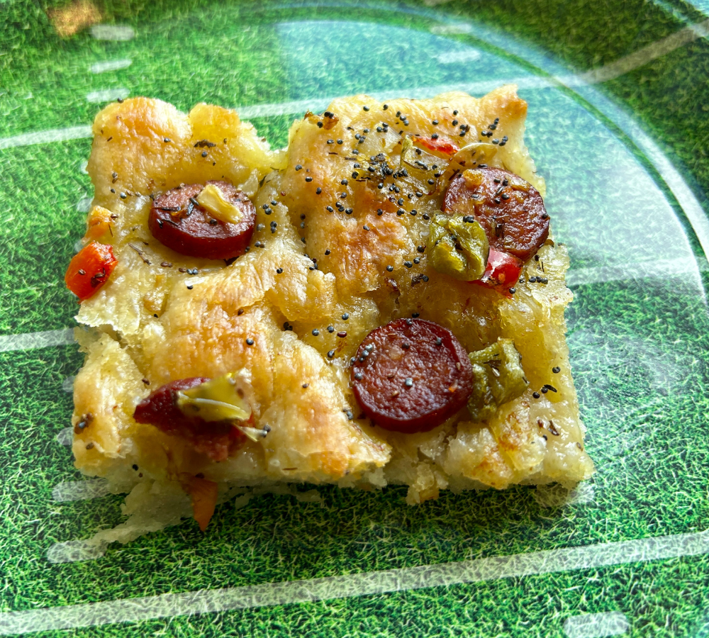 A green plate with a piece of focaccia bread.