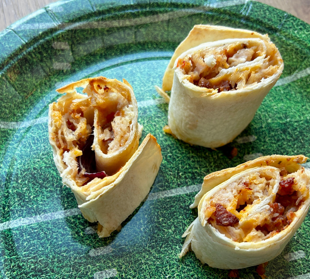 A green plate with three tortilla roll-ups