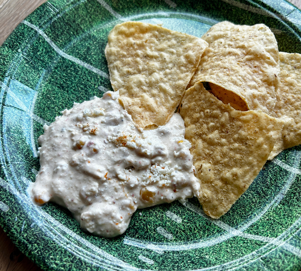 A green plate with dip and torilla chips.