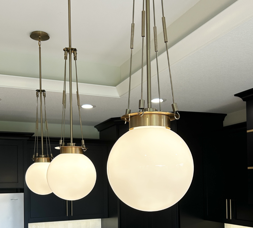 three round white glass albers pendant lights by Kichler installed above kitchen island