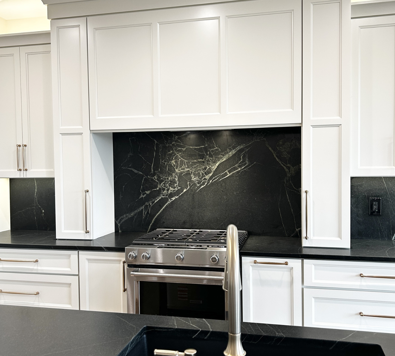 white painted cabinet range hood design with black backsplash and cabinets that go down to counters