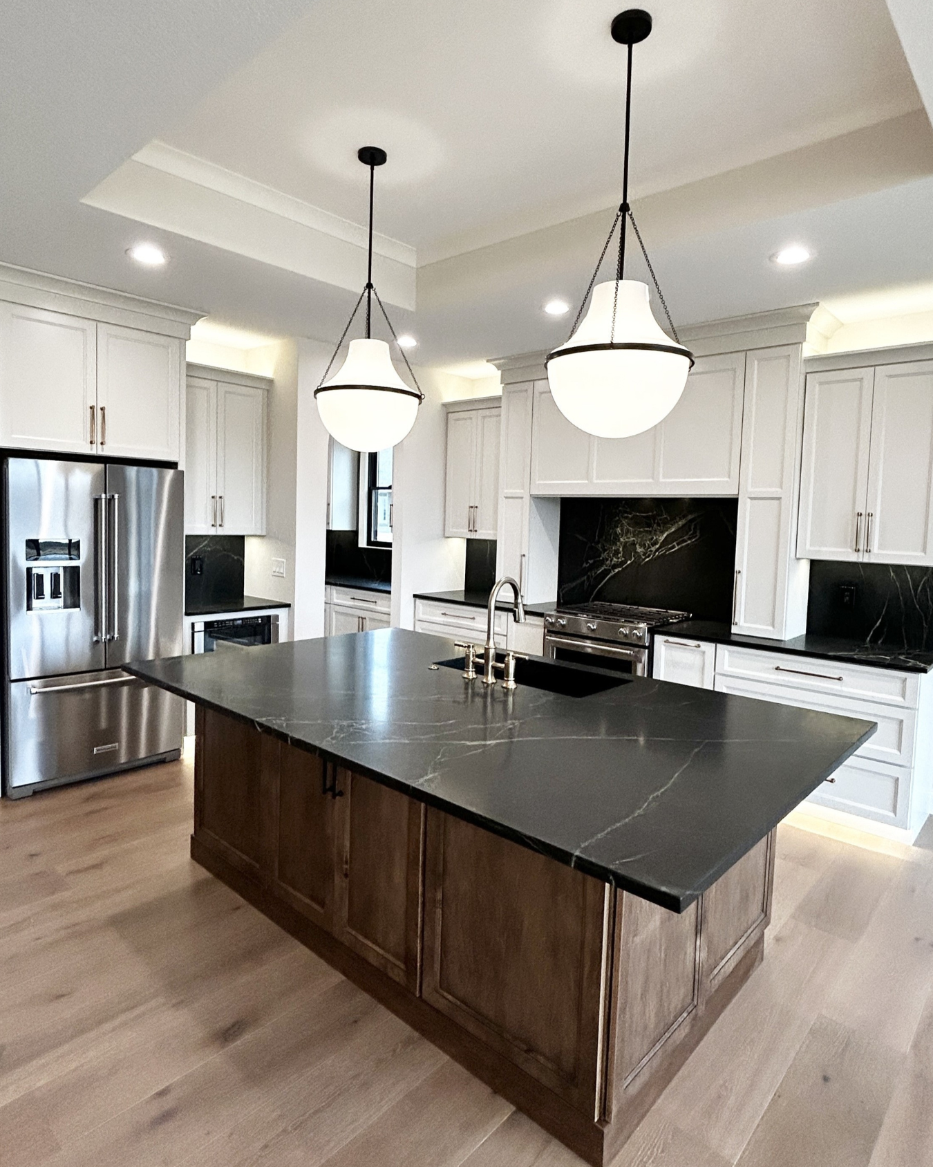 shoji white painted cabinet kitchen with large maple island with black counters and two pendant lights hanging above