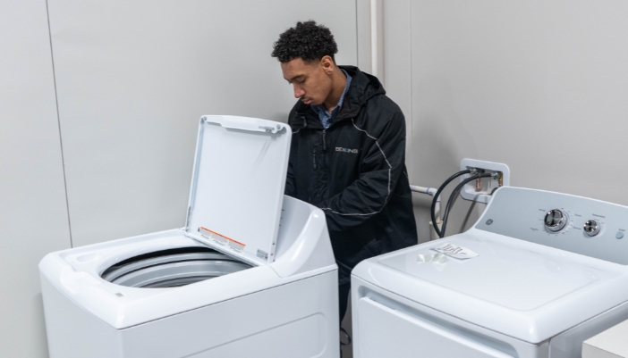 A service technician works on a dryer in a home.