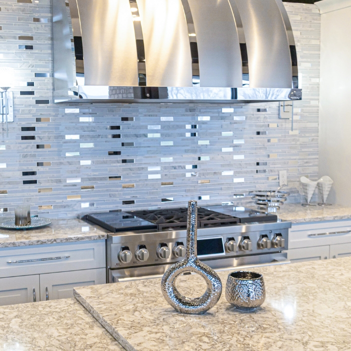 A kitchen range in a modern kitchen with a whtie and metallic backsplash.