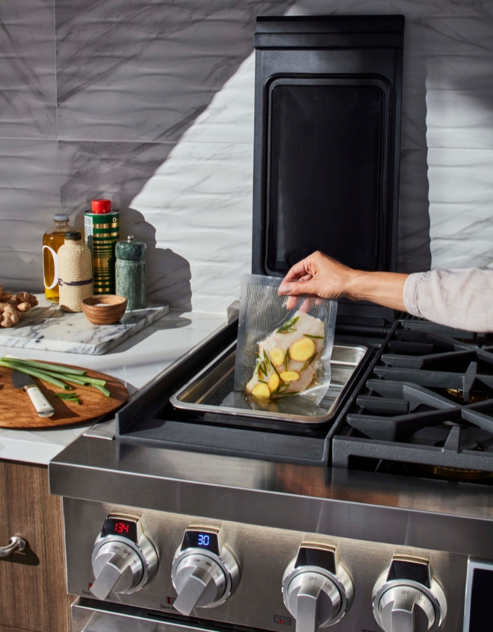 A hand sticks food into a sous vide to cook
