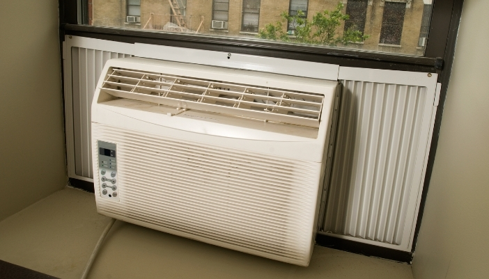 White window air conditioner unit installed in a home window with the control panel visible