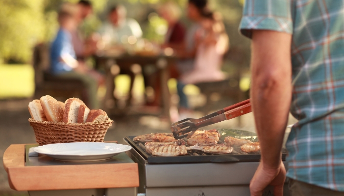 An over the shoulder look of a man grilling at home.