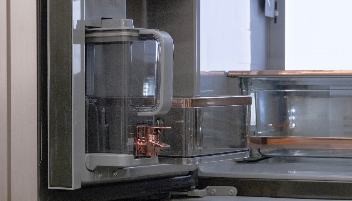 Close-up of an internal water dispenser pitcher with a copper-finish spout inside a refrigerator door