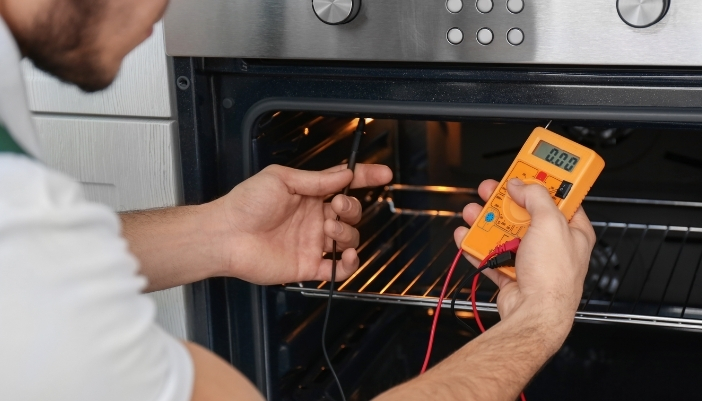 Appliance repair technician replacing a part inside a home refrigerator