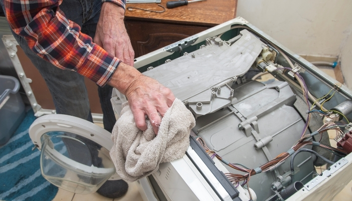 Certified service technician performing an appliance repair in a customer's kitchen