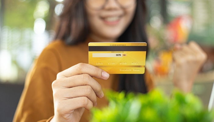 A close-up of a woman holding a gold credit card.