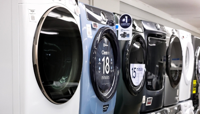 A line of different finishes of washers in an appliance showroom.