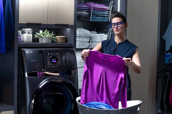  A woman taking a purple sweater out of the GE Profile PFQ97HSPVDS