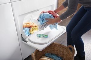 woman retrieving clothes from dryer with drop down door