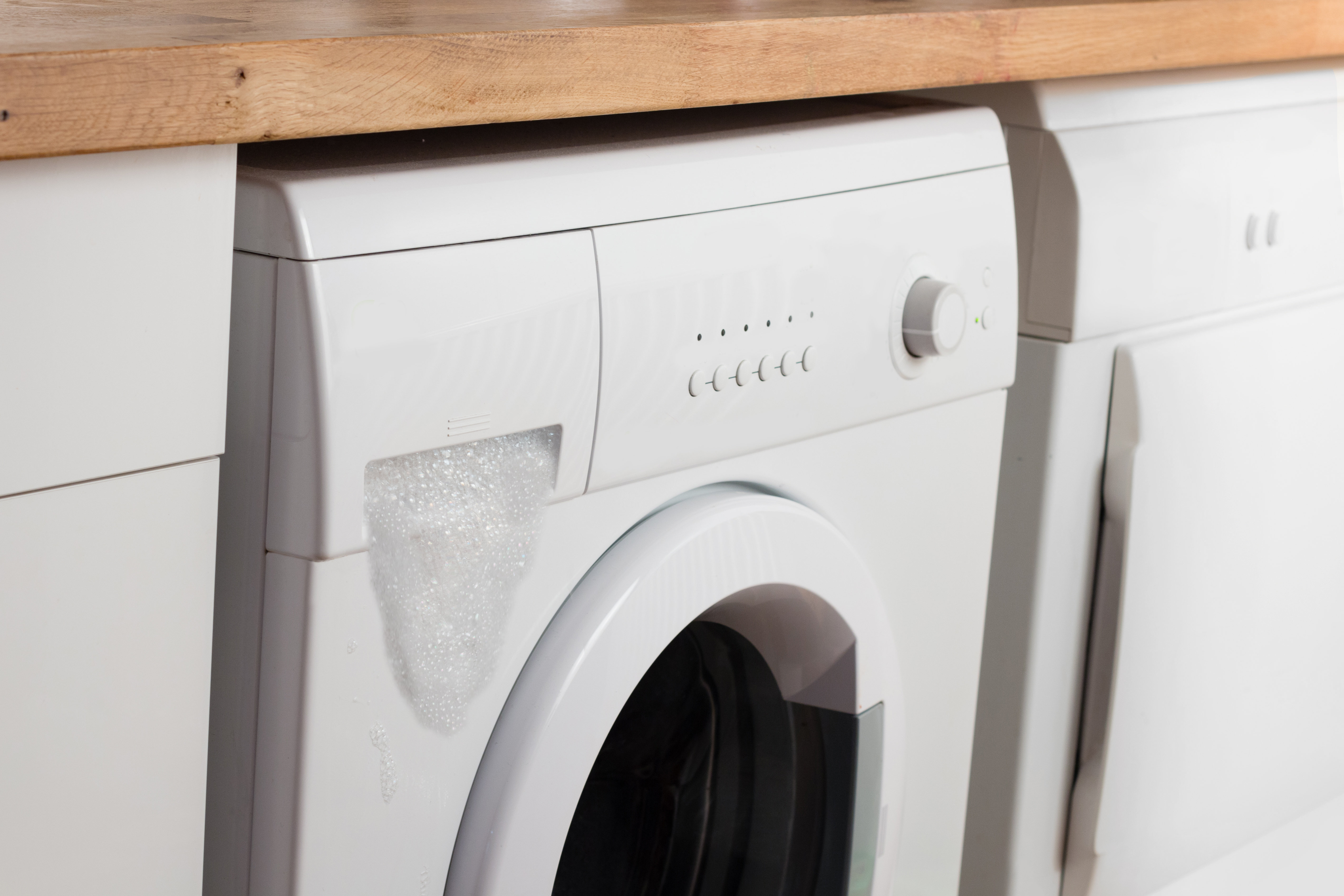 Front load washer with suds spilling out from detergent dispenser