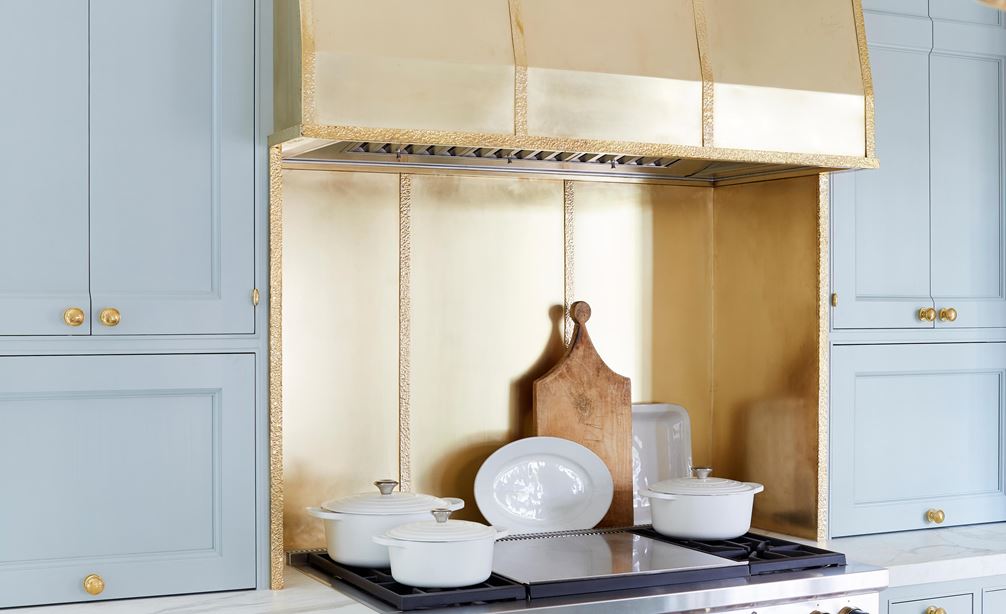 A custom Wolf hood liner in brass show in a kitchen designed by Matthew Quinn 