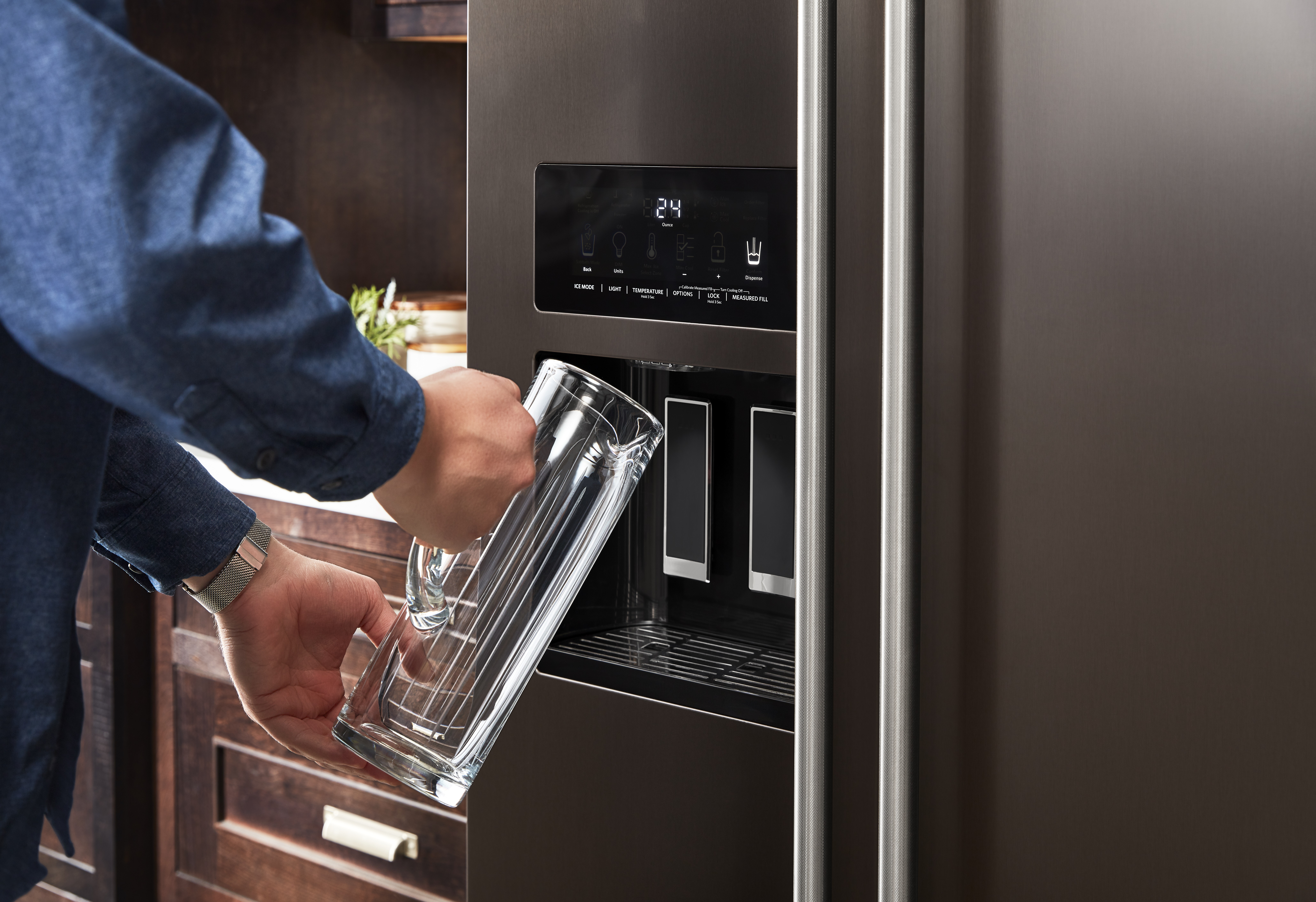 Person using water dispenser on KitchenAid krsf705hbs French door refrigerator 