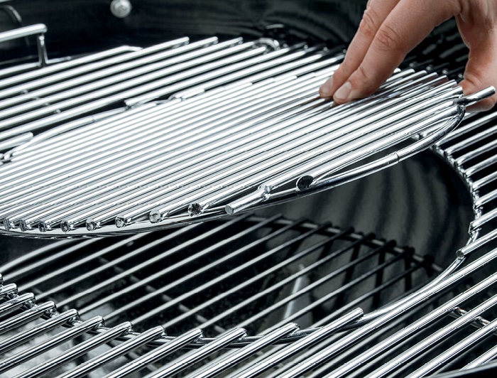 Person removing the hinged grates from Weber 15501001 charcoal grill