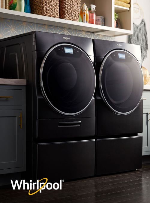 Black front load Whirlpool washer and dryer mounted on pedestals