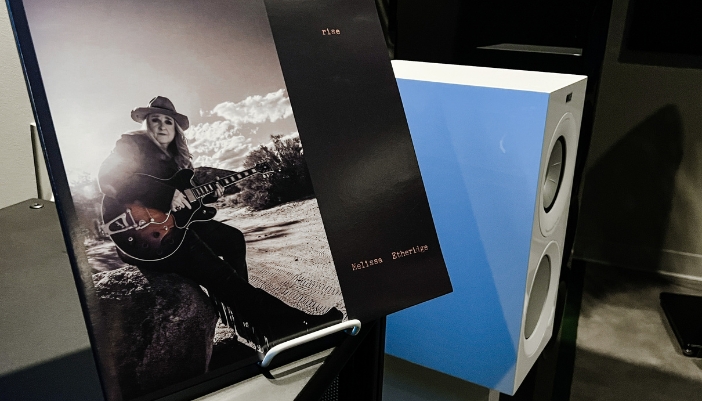 A closeup of a record next to a white speaker.