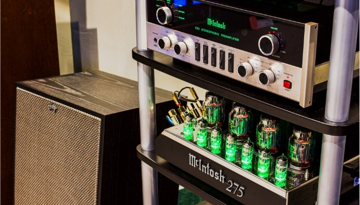 A McIntosh amplifier on black shelves with silver accents.