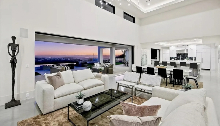 Open living room with wide glass doors framing a lit patio and sunset view at a Rancho Santa Fe home