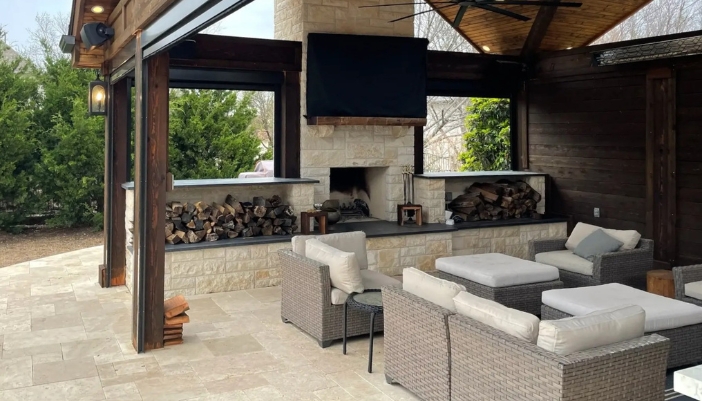 An outdoor patio space with a TV and a fireplace + wood.