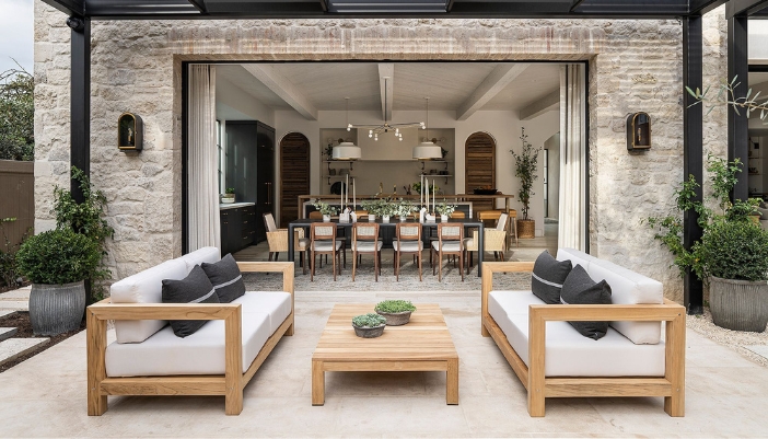 A luxury outdoor living space with two couches and a coffee table and stone accents.
