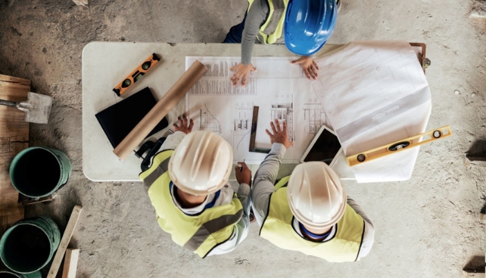 An overhead view of construction workers looking at blueprints.